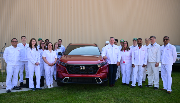 A group of Honda employees stand beside a red Honda vehicle posing and smiling. 